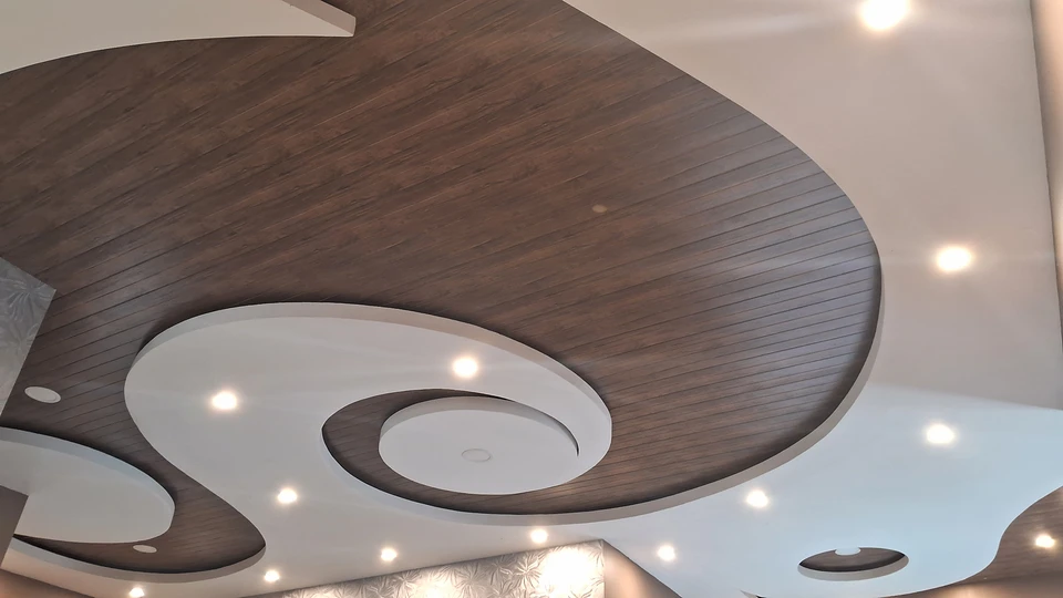 Intérieur de maison en construction avec cheminée moderne encastrée, murs en plaques de plâtre non peints, plafond à caissons avec poutres apparentes blanches