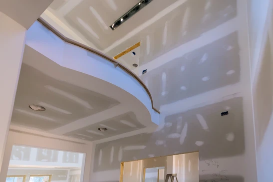 Un artisan installe un plafond suspendu dans un intérieur blanc