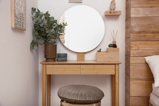 Main posant une plinthe en bois contre un mur blanc sur parquet stratifié
